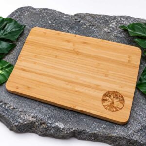Houten snijplank van bamboe met Tree of Life gravure op donkere steen met groene bladeren