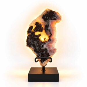 Roze Amethist Eclipse lamp op zwarte standaard met warme verlichting en donkere natuurlijke mineraalstructuren