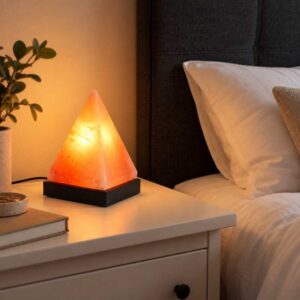 Zoutlamp Peak met piramidevormige zoutsteen op zwarte voet in sfeervolle slaapkamer