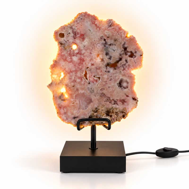 Roze Amethist Edelsteen Lamp Pink Moon met natuurlijke roze kristalstructuren, warme achtergrondverlichting en zwarte metalen standaard.