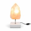 Rozenkwarts Rose Flame mineraallamp met witte vierkante voet, chromen standaard en warme verlichting in een natuurlijke kristalpunt.