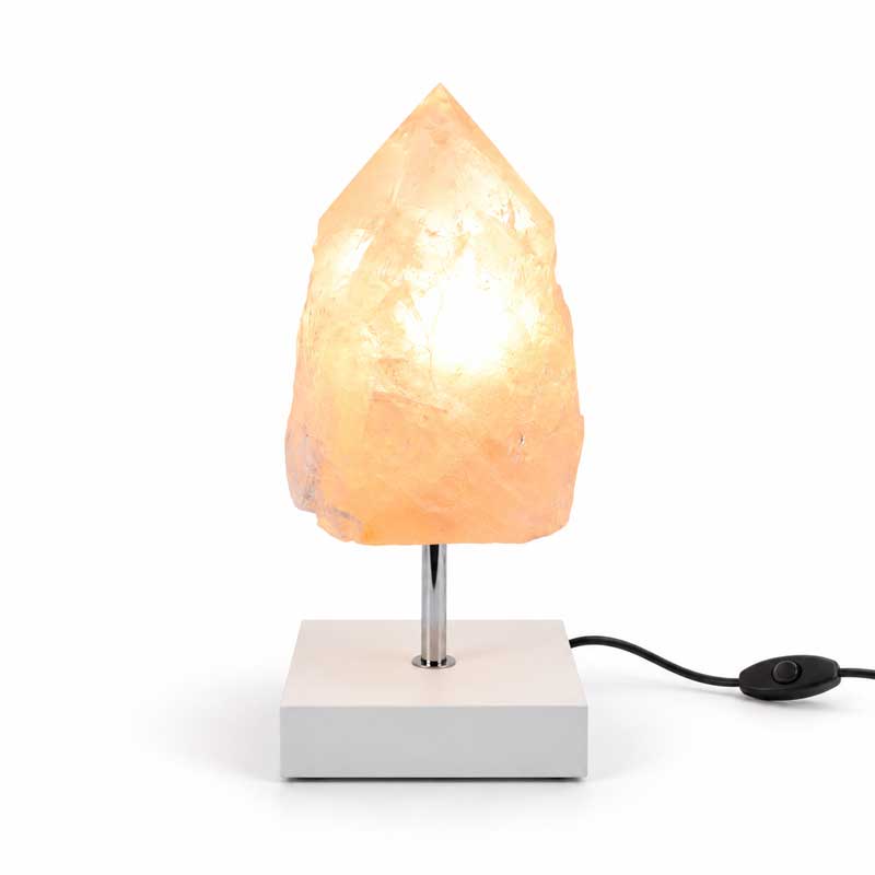 Rozenkwarts Rose Flame mineraallamp met witte vierkante voet, chromen standaard en warme verlichting in een natuurlijke kristalpunt.
